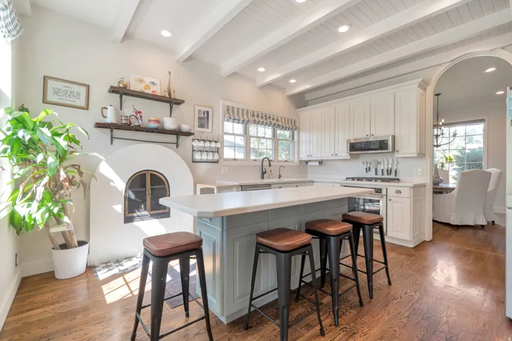 Wood-finish flooring, white coffered ceiling, built-in kitchen island with seating, arched doorway, and built-in fireplace