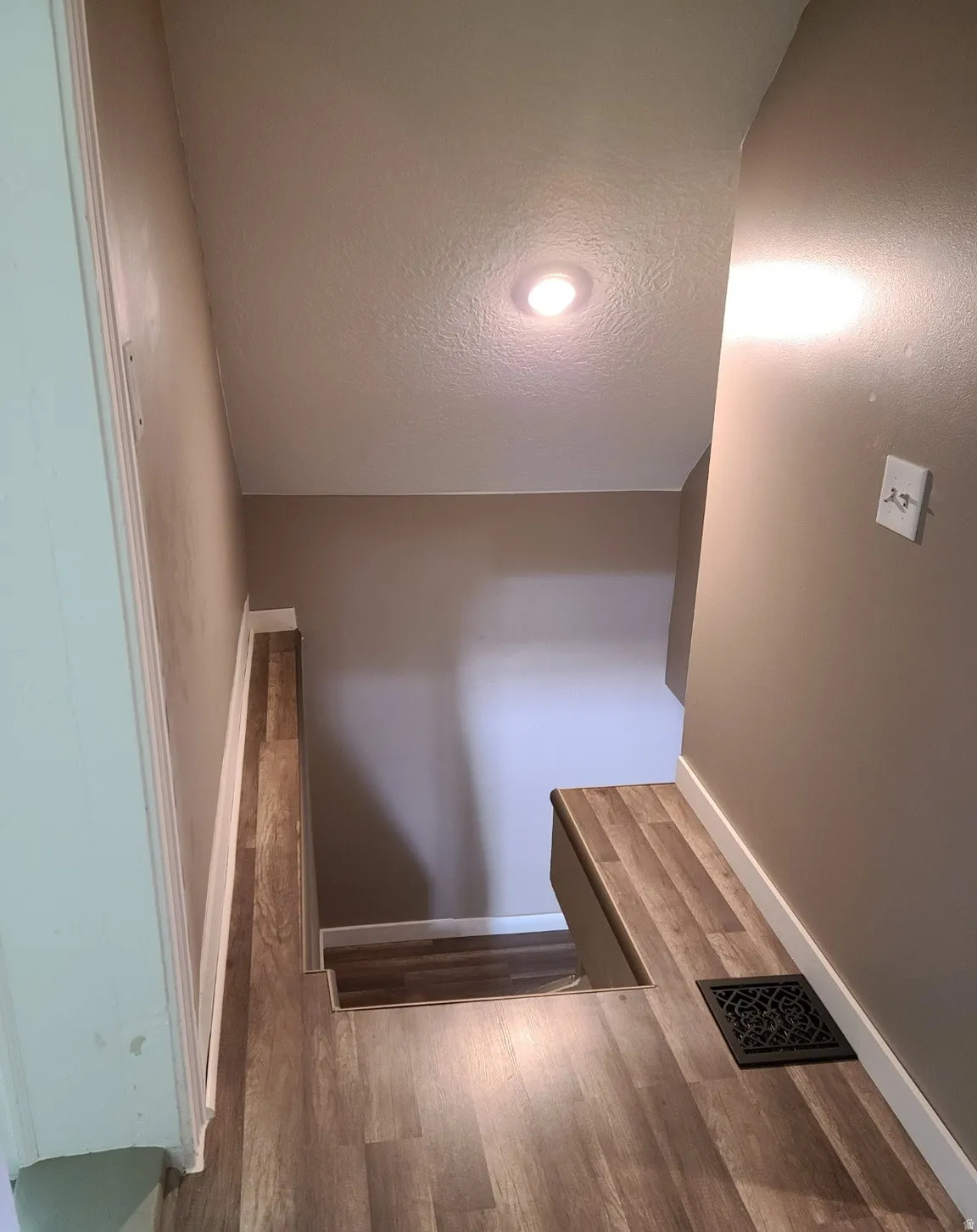 Wood-finish flooring with white trim and recessed ceiling lighting