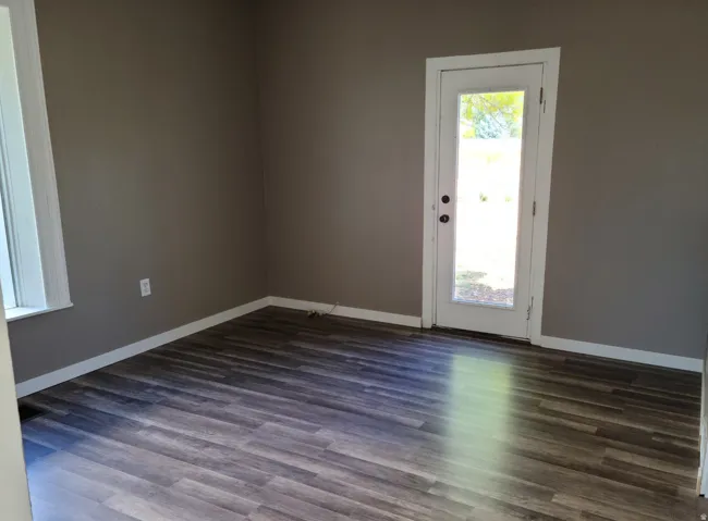Wood-finish flooring, neutral wall color, white trim, and a full-light exterior door