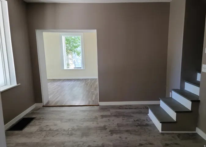 Wood-finish flooring throughout, framed doorway, and a multi-level staircase