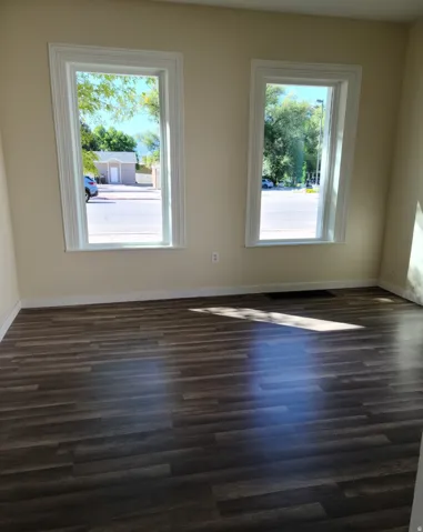 Wood-finish flooring with light-toned walls and two windows featuring white trim
