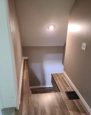 Wood-finish flooring with white trim and recessed ceiling lighting