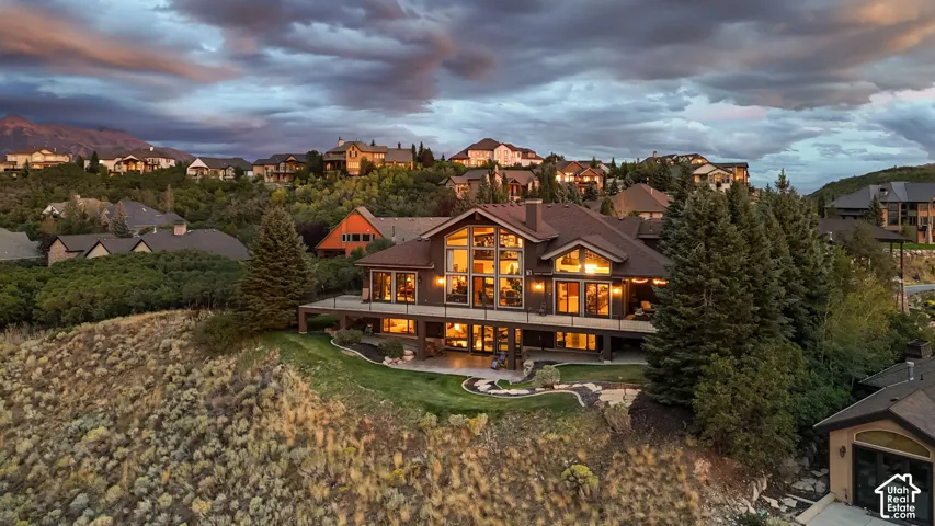 Expansive multi-level residence with a wood and stone-look exterior, extensive deck space, large windows, and a manicured lawn