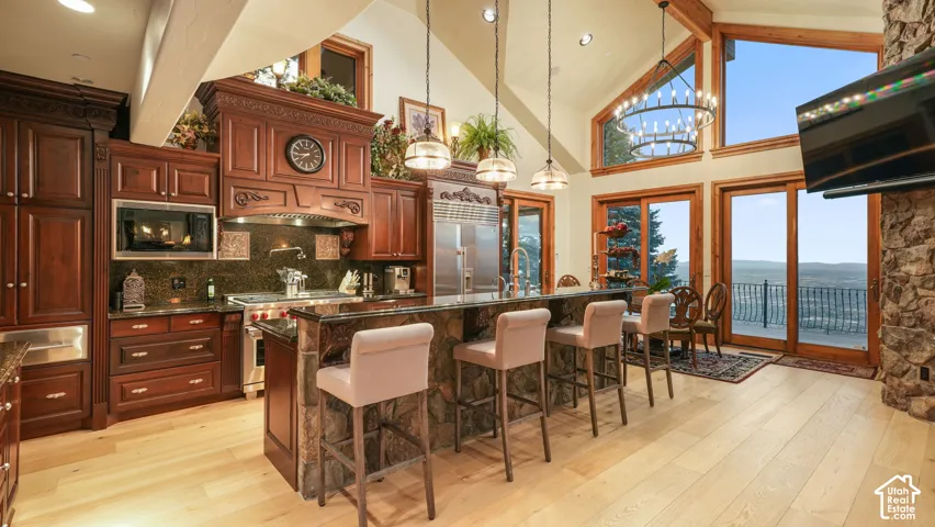 Hardwood flooring paired with a stone- kitchen island, dark heavy wood cabinetry, and stainless steel Wolf and SubZero appliances.