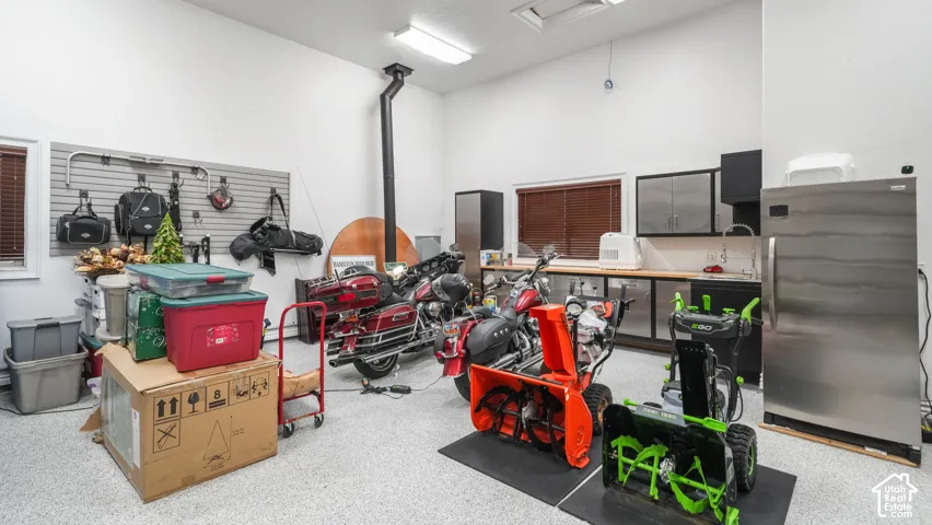 Spacious garage featuring a durable epoxy floor, integrated slatwall storage system, built-in cabinetry with stainless steel accents, and a utility sink