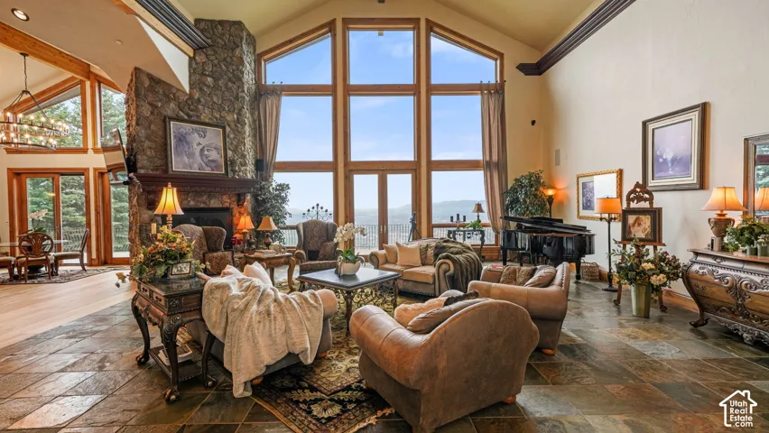 Soaring ceilings, stone  fireplace, expansive picture windows, stone flooring, and light wood-finish flooring