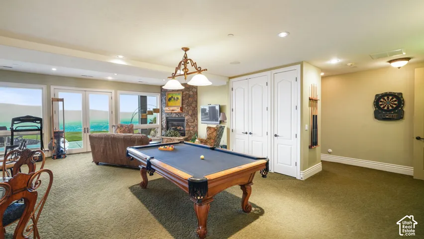 Expansive recreation room featuring a stone ireplace, built-in cabinetry, recessed lighting, and a walk-out to the exterior