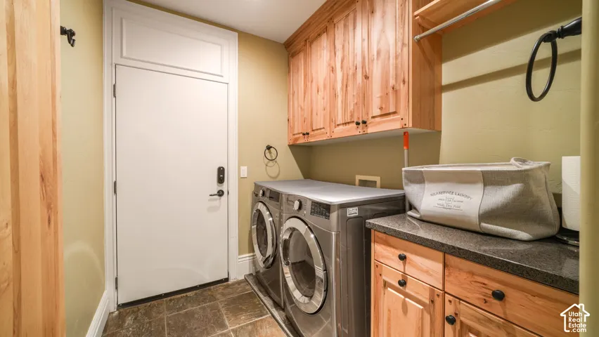 Guest Quarters Private Laundry area with wood cabinetry, dark countertop, and stone flooring