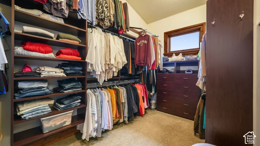 Spacious Master Suite Walk-in closet with Built-in shelving, hanging storage, integrated drawer unit, and window with wood-finish trim