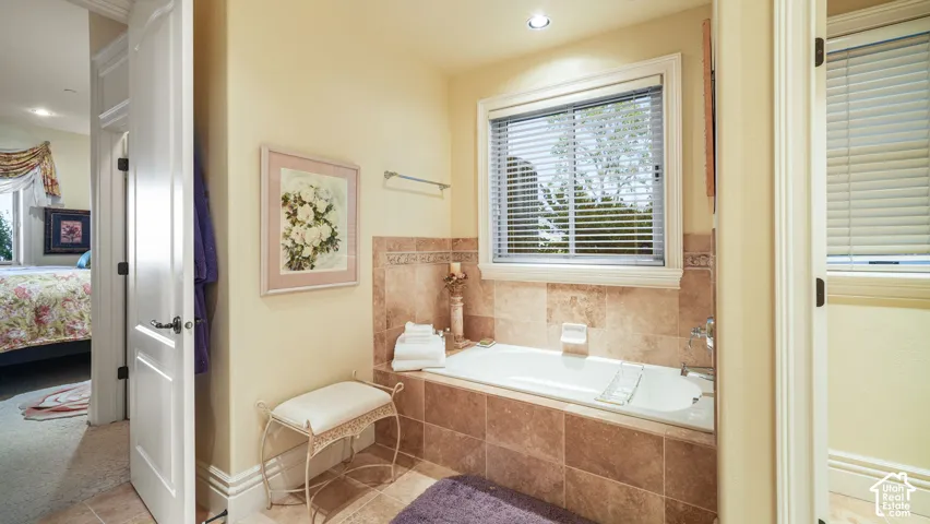 Built-in soaking tub with stone tile surround, recessed lighting