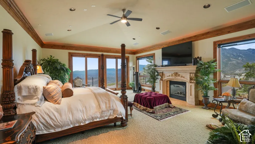 Master suite with panoramic views- featuring a decorative fireplace with an ornate mantelpiece, expensnive wood trim, multiple windows, and glass sliding doors leading to a balcony