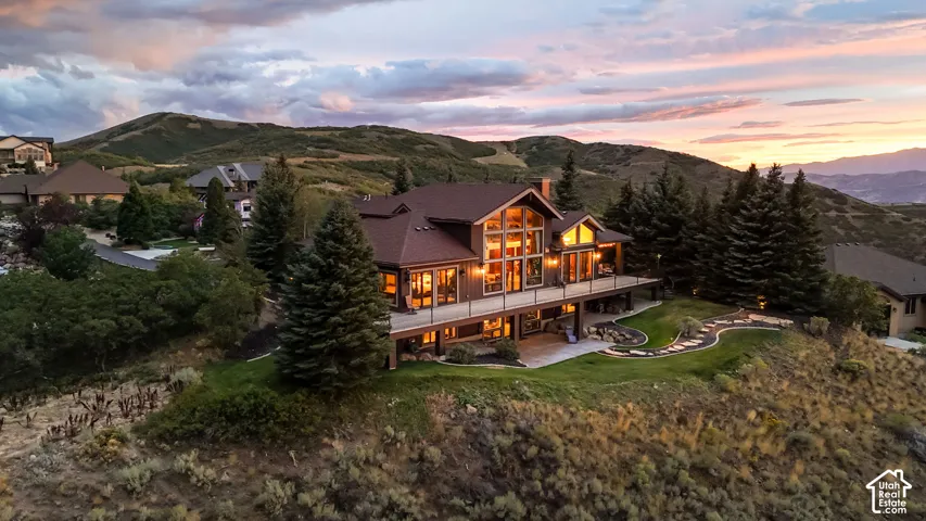 Multi-story residence featuring a prominent balcony, extensive window walls, and terraced landscaping