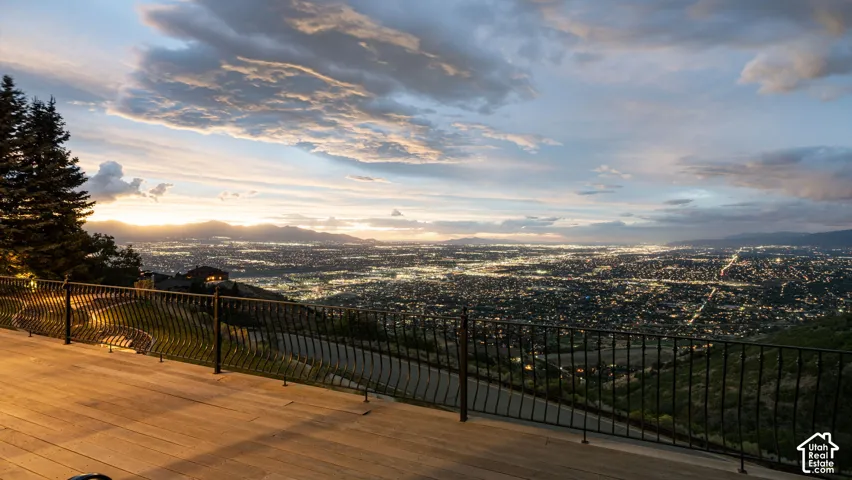Expansive outdoor decking with metal railing overlooking distant city lights and mountains