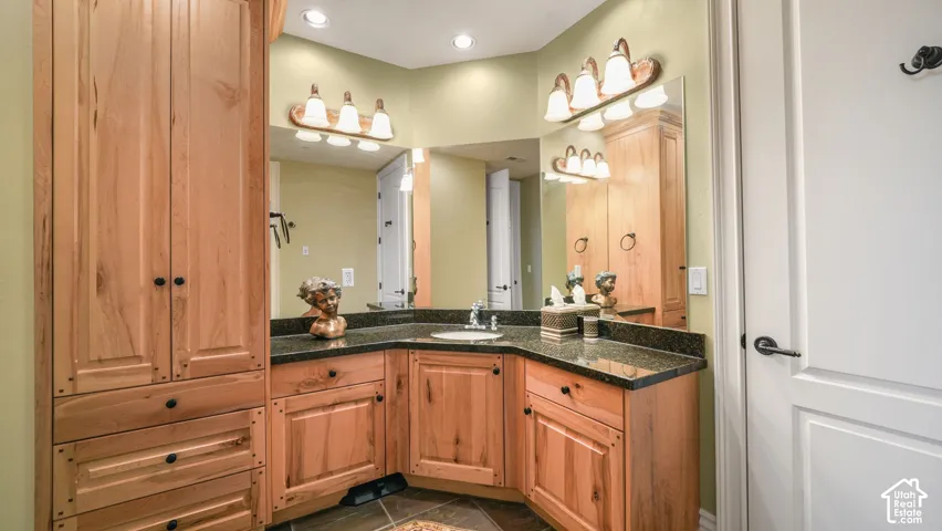 Natural wood cabinetry with ample storage, dark countertop, and an undermount sink