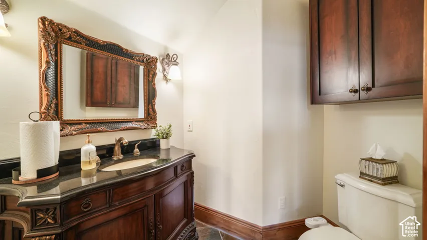 Master powder room with Ornate vanity with a dark countertop, undermount sink, and wall-mounted sconces