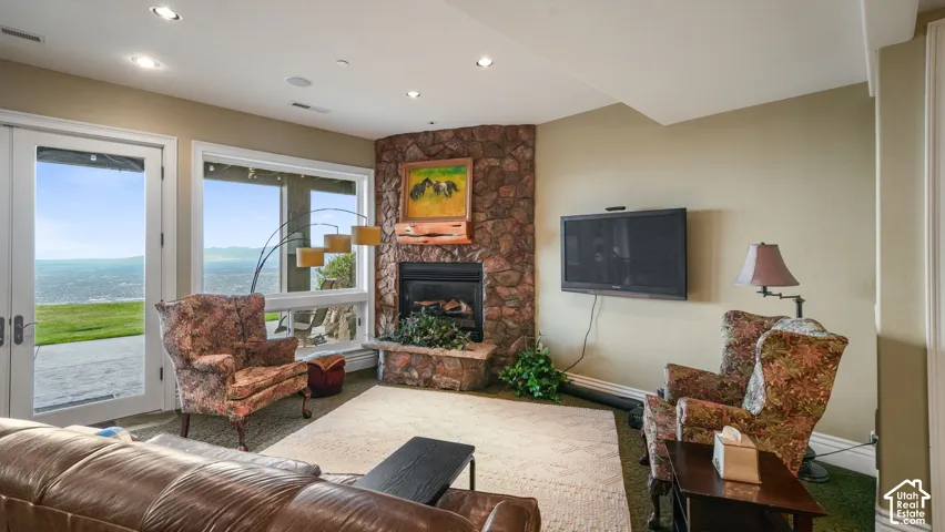 Stone fireplace with a hearth, large windows, recessed ceiling lighting, and glass-paneled double doors