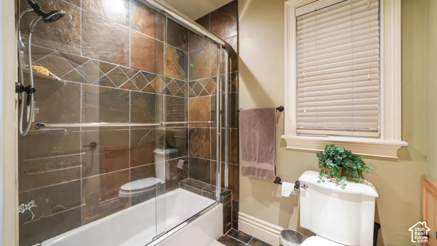 Bathtub with a glass shower enclosure, multi-tone tile surround, and a ceiling-mounted showerhead