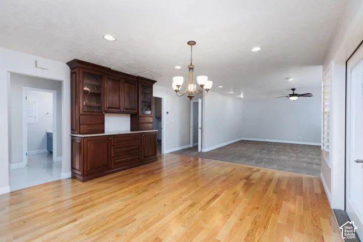 Wood-finish flooring, built-in cabinetry with glass display doors, recessed lighting, and a ceiling fan