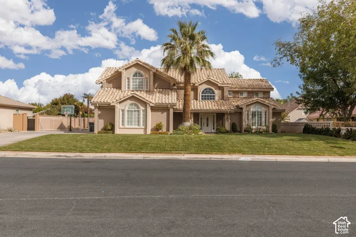 Stucco exterior with a tiled roof, arched windows, and a prominent palm tree