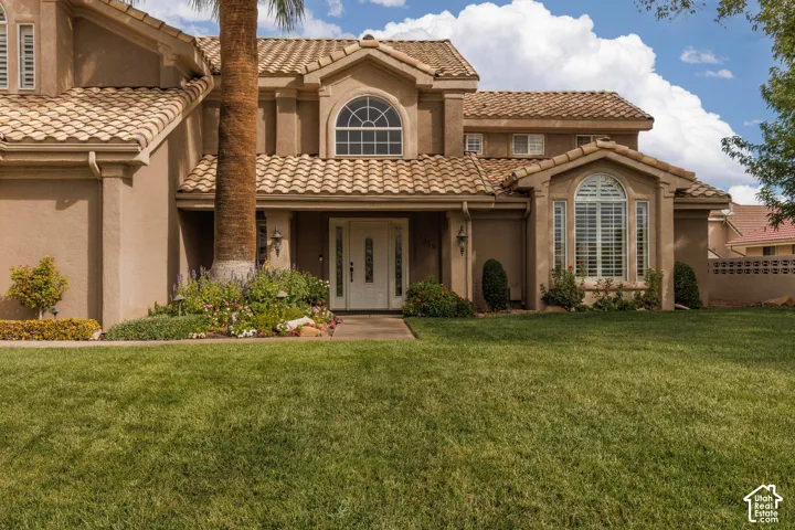 Stucco exterior with a tiled roof, arched window, and decorative front entry