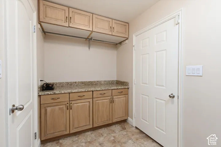 Granite-finish countertop with built-in cabinetry, upper storage cabinets, and a hanging rod