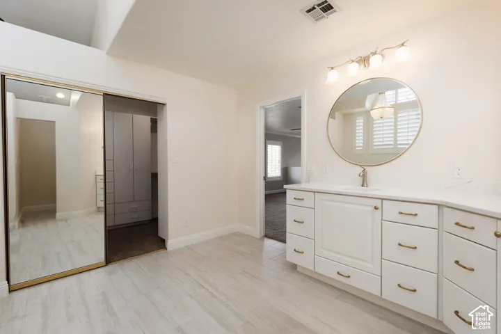 White vanity with brass hardware, undermount sink, and a circular mirror