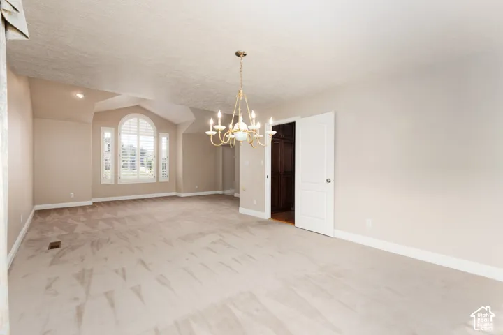 Tray ceiling, arched window, plantation shutters, recessed lighting, and a gold-finish chandelier