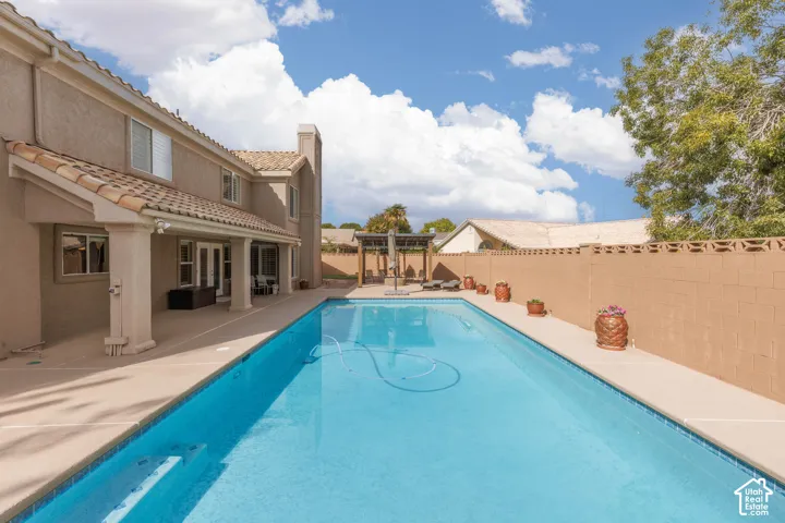 Expansive outdoor space featuring a rectangular swimming pool, a spacious covered patio, a stucco exterior, and a tile roof