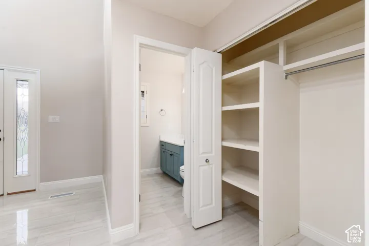 White tile flooring, built-in shelving, white trim, and a frosted glass door
