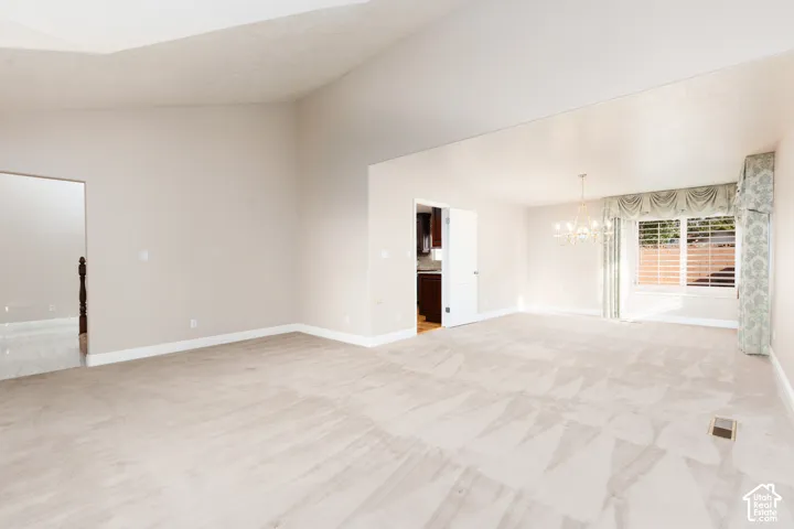 Vaulted ceiling, neutral carpet flooring, recessed lighting, chandelier lighting, and a window with plantation shutters
