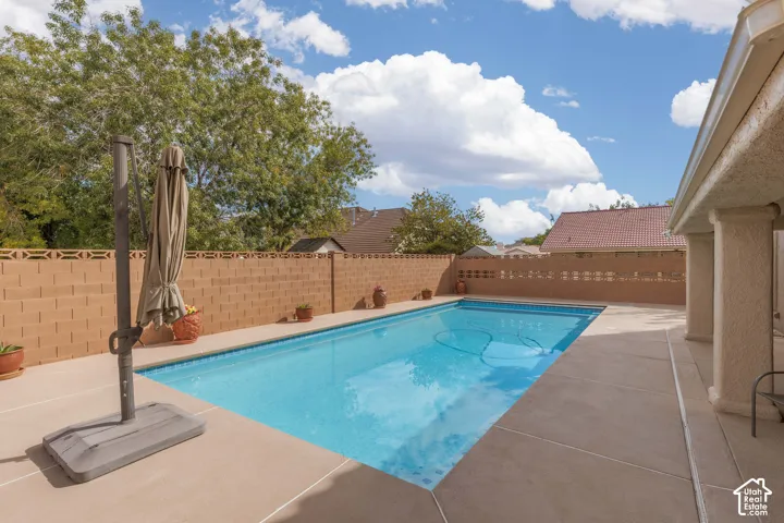 Rectangular swimming pool with light blue water, surrounded by concrete decking and a block perimeter wall