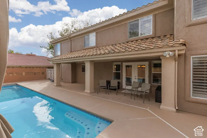 Exterior featuring a tile roof, stucco finish, covered patio, and a swimming pool with integrated steps