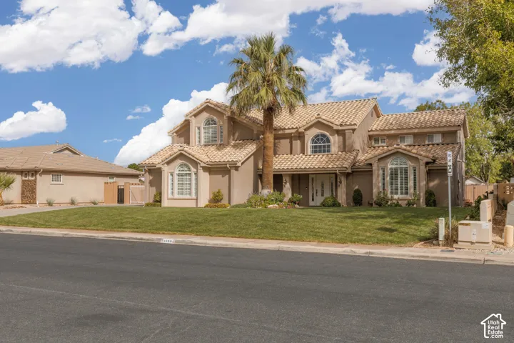 Stucco exterior with a tiled roof, arched windows, and a manicured lawn