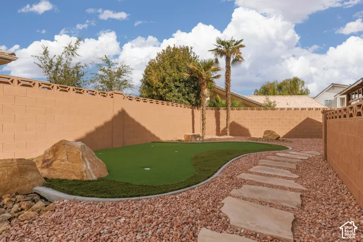 Backyard featuring a putting green, a flagstone path, decorative rock ground cover, and mature palm trees