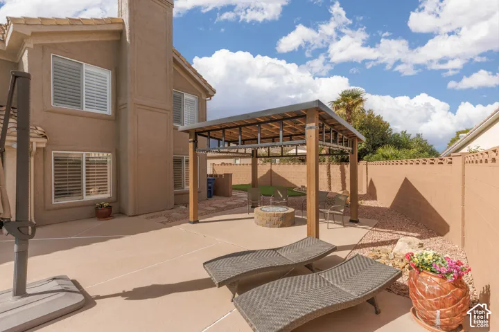 Expansive concrete patio with a modern pergola, built-in fire pit, and privacy fencing