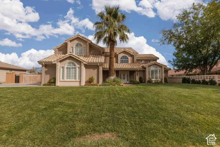 Stucco exterior with a tile roof, arched windows, and a prominent palm tree