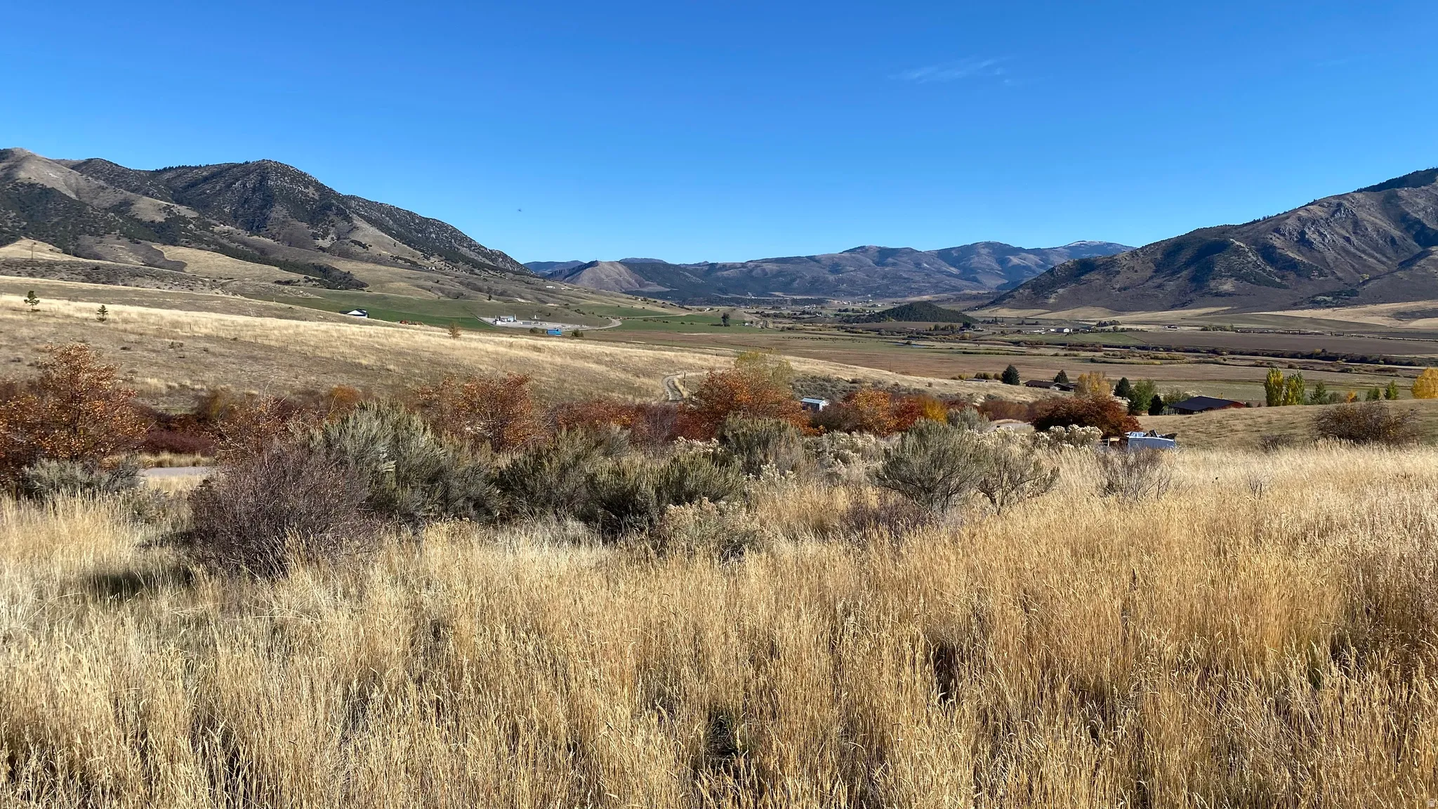 Expansive landscape featuring rolling hills and distant mountains under a clear sky