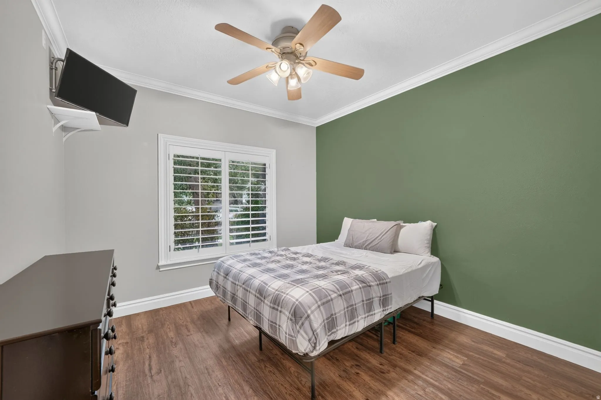 Wood-finish flooring, crown molding, and a ceiling fan with integrated lighting