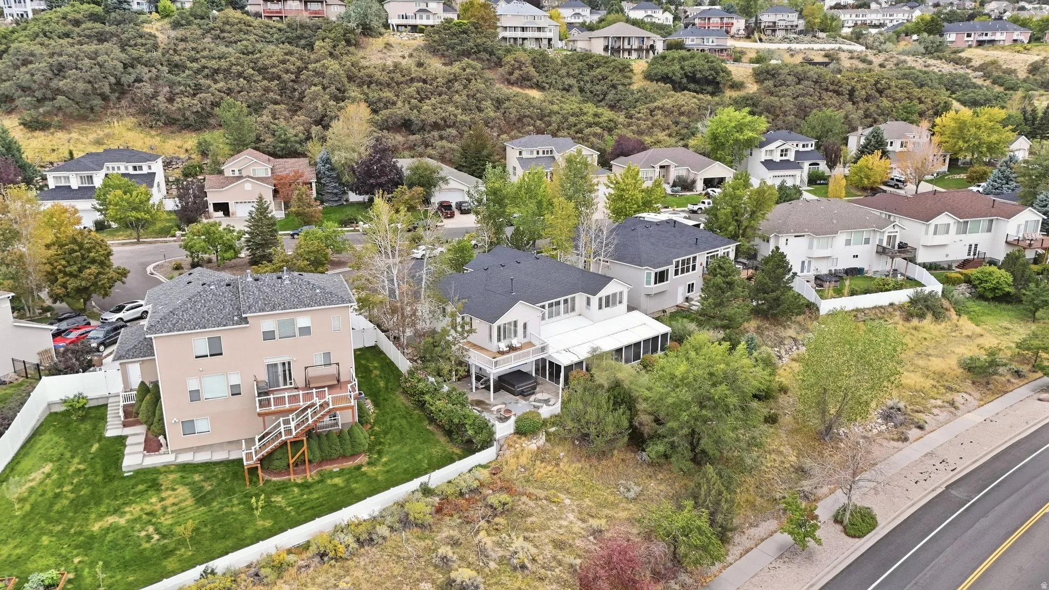 Expansive residential property featuring a multi-level deck with stairs, a manicured lawn, and mature landscaping