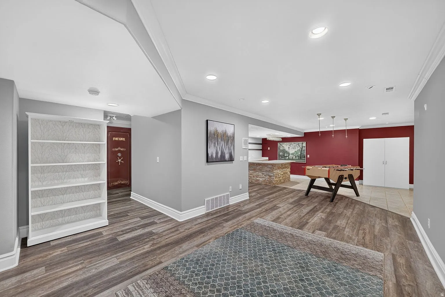 Spacious recreation area featuring wood-finish flooring, recessed lighting, and crown molding