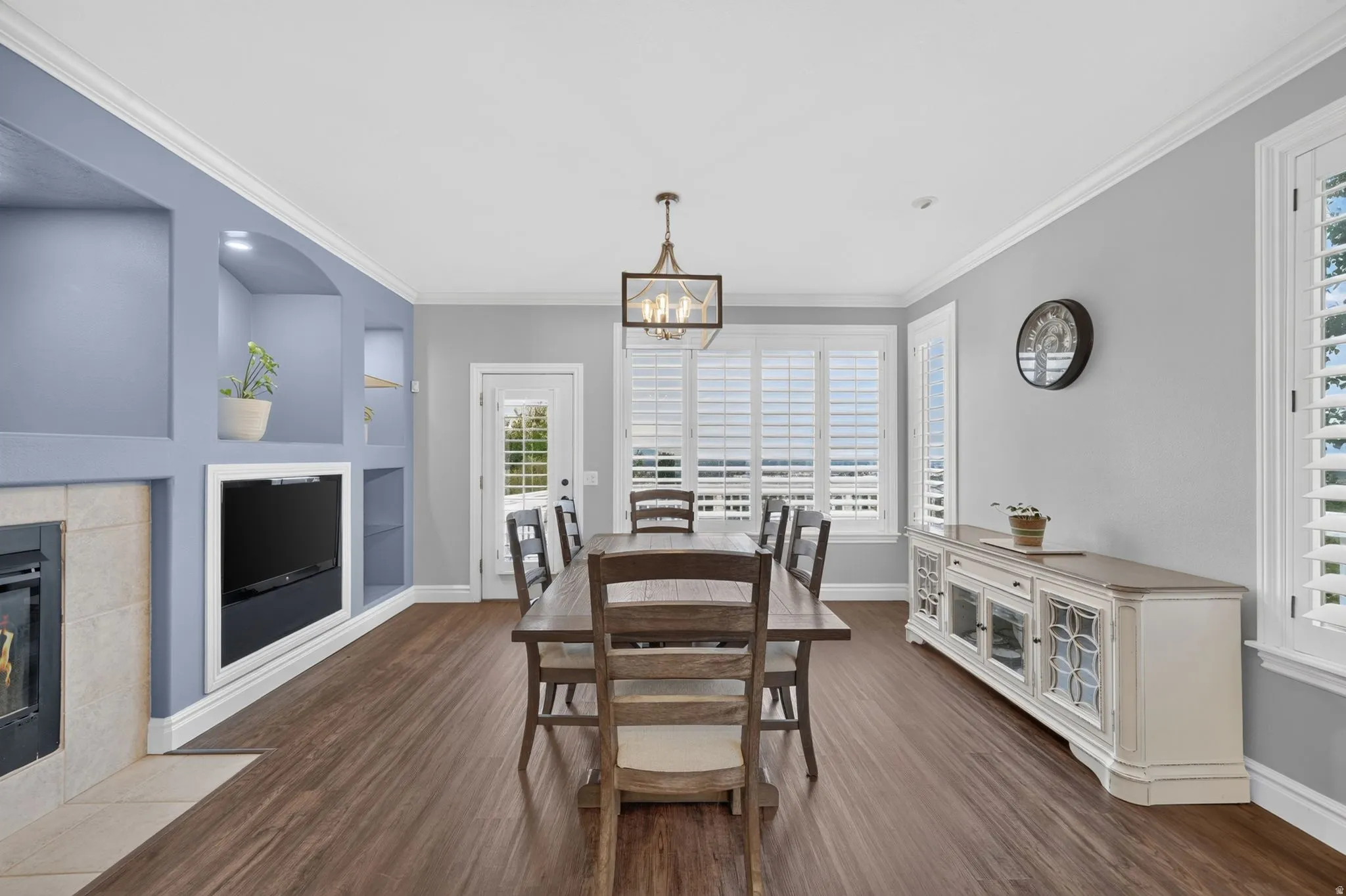 Built-in shelving and media cabinet, wood-finish flooring, crown molding, and plantation shutters