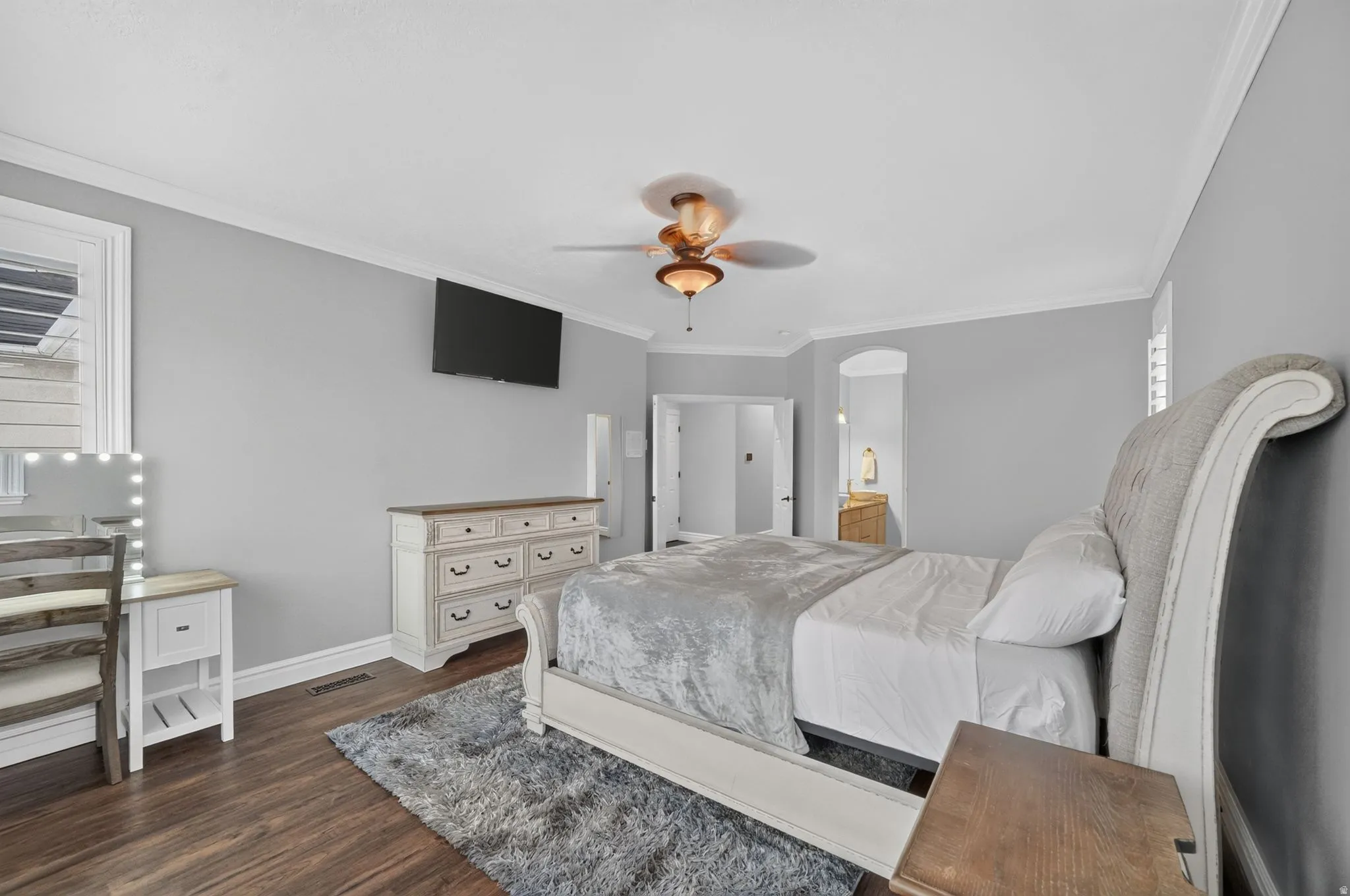 Wood-finish flooring, crown molding, and a ceiling fan with integrated lighting