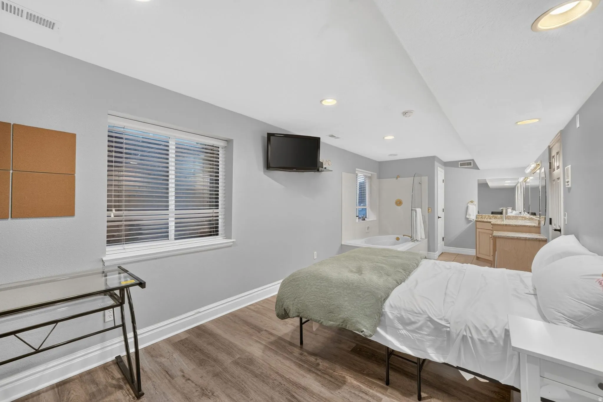 Wood-finish flooring, recessed lighting, double vanity, built-in bathtub, and a separate glass-enclosed shower