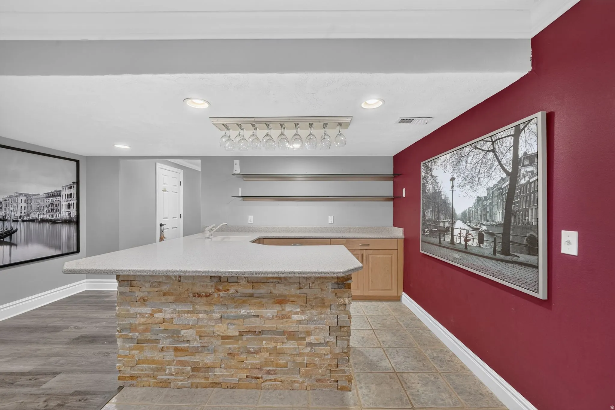 Built-in wet bar with a stone-clad island, light-toned cabinetry, and integrated shelving
