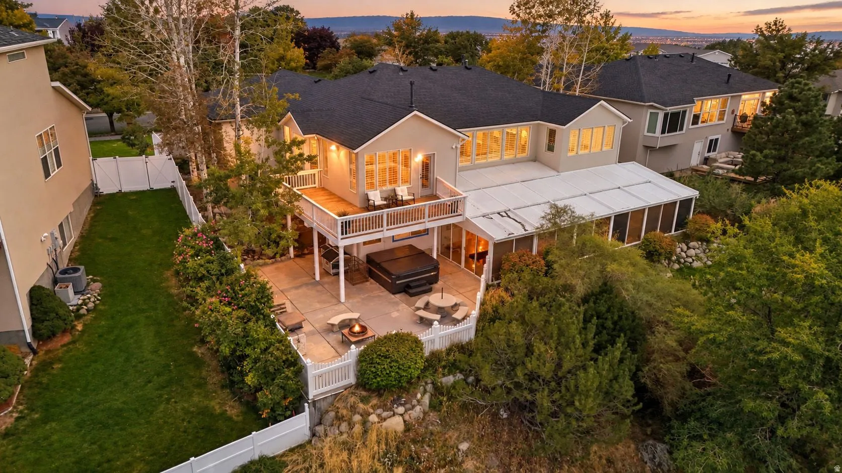 Expansive rear elevation featuring multiple levels, an upper deck, a lower patio, and an enclosed sunroom