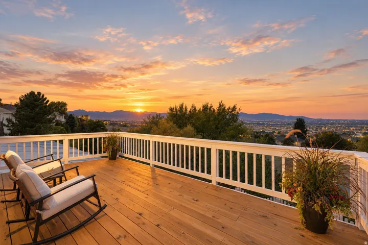 Expansive outdoor deck featuring wood-finish flooring, white railing, and distant mountain scenery