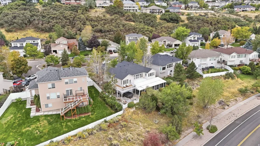 Expansive residential property featuring a multi-level deck with stairs, a manicured lawn, and mature landscaping