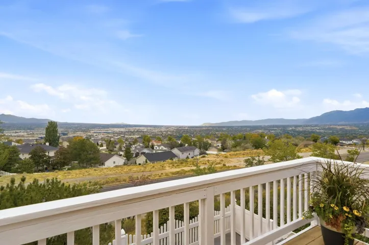 Deck with white railing overlooking distant mountains and a residential landscape