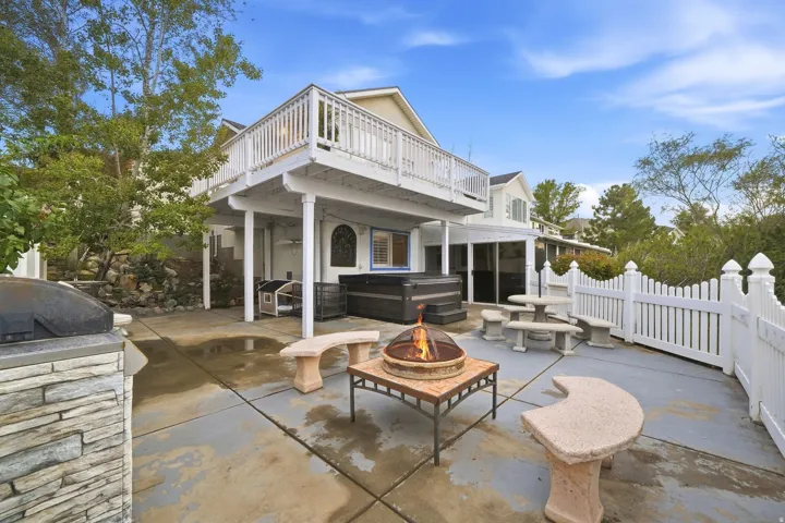 Expansive patio featuring a built-in barbecue with stone facade, hot tub, and upper-level deck