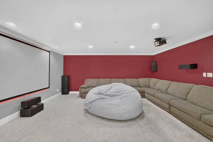 Recessed lighting, crown molding, a large projector screen, and wall-mounted speakers define this entertainment space